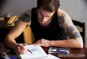 Фотография мастера тату, рисующего эскиз татуировки. Видны его руки, карандаш и лист бумаги с наброском. Процесс создания уникального рисунка татуировки.
